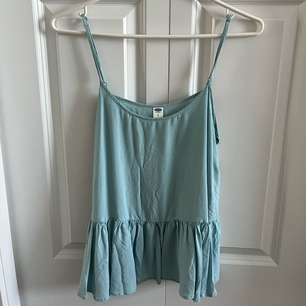 Blue tank top with adjustable straps and peplum detailing  along the bottom.
